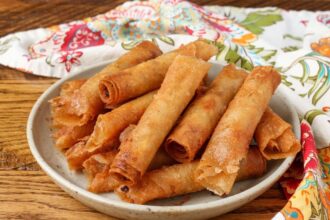 pottery plate stacked with lumpia next to napkin on table