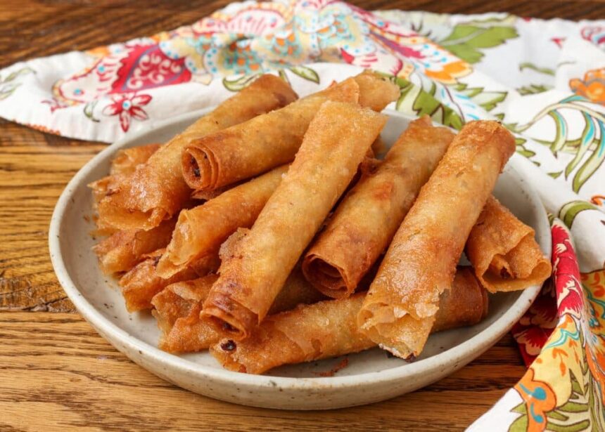 pottery plate stacked with lumpia next to napkin on table