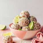 Bowl of no-bake coconut lime energy bites and lime slices