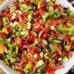horizontal overhead photo of a loaded salad with salami and cheese
