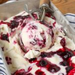 lemon blueberry swirl ice cream in a pan with a scoop
