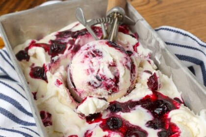 lemon blueberry swirl ice cream in a pan with a scoop