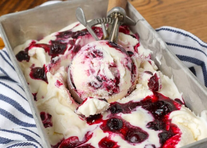 lemon blueberry swirl ice cream in a pan with a scoop