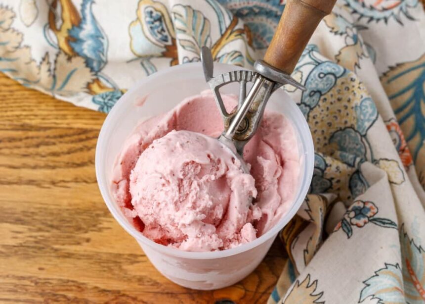horizontal photo of ice cream in container with scoop on wooden table