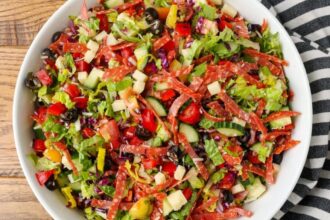 horizontal overhead photo of a loaded salad with salami and cheese