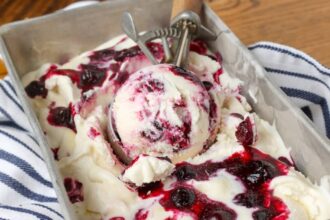 lemon blueberry swirl ice cream in a pan with a scoop