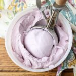 grape ice cream in bowl with wooden scoop