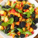 peaches and blackberries and herbs on white plate