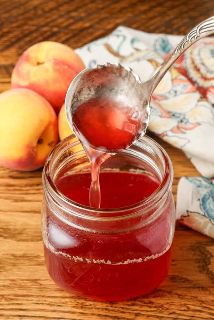 peach syrup in jar with silver ladle
