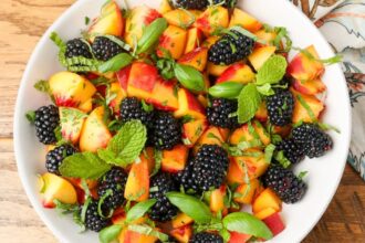 peaches and blackberries and herbs on white plate