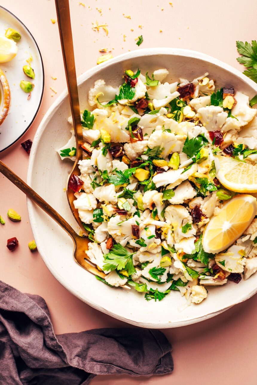 Fork and spoon resting in a bowl of our raw chopped cauliflower salad recipe