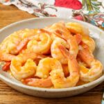 shrimp with an orange garlic sauce on pottery plate