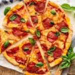 Close-up of pepperoni cottage cheese pizza with melted cheese and basil.