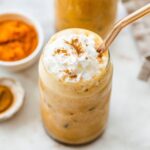 Iced pumpkin spice latte topped with whipped cream and a sprinkle of cinnamon.