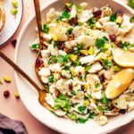 Fork and spoon resting in a bowl of our raw chopped cauliflower salad recipe