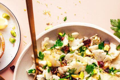 Fork and spoon resting in a bowl of our raw chopped cauliflower salad recipe