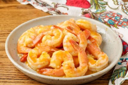 shrimp with an orange garlic sauce on pottery plate
