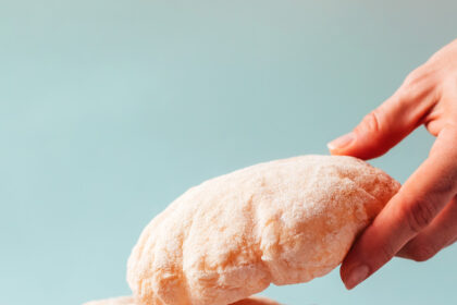 Hand reaching in to pick up a piece of gluten-free pita from a stacked plate of pita