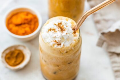 Iced pumpkin spice latte topped with whipped cream and a sprinkle of cinnamon.