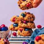 Picking up a vegan gluten-free oatmeal monster cookie from a stack of more cookies