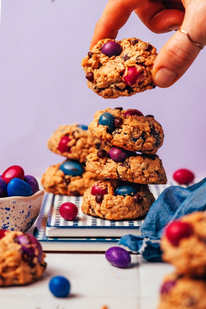 Picking up a vegan gluten-free oatmeal monster cookie from a stack of more cookies