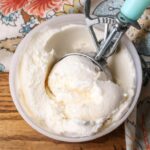 A top down image of a freezer safe container of ice cream on a wooden tabletop.