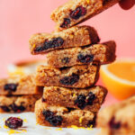Picking up a gluten-free cranberry orange cookie bar from a stack of more cookie bars