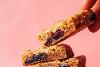 Picking up a gluten-free cranberry orange cookie bar from a stack of more cookie bars