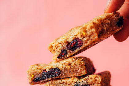 Picking up a gluten-free cranberry orange cookie bar from a stack of more cookie bars