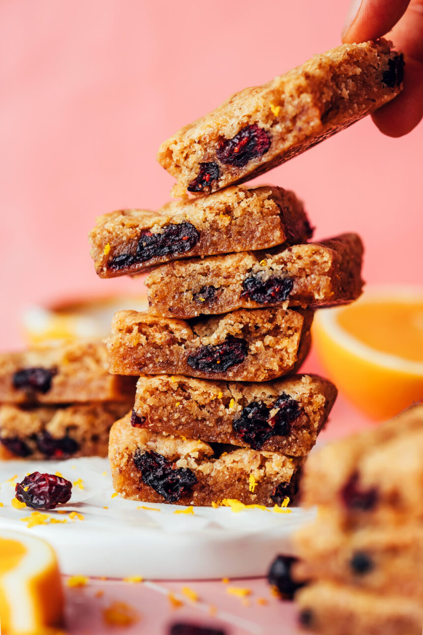 Picking up a gluten-free cranberry orange cookie bar from a stack of more cookie bars