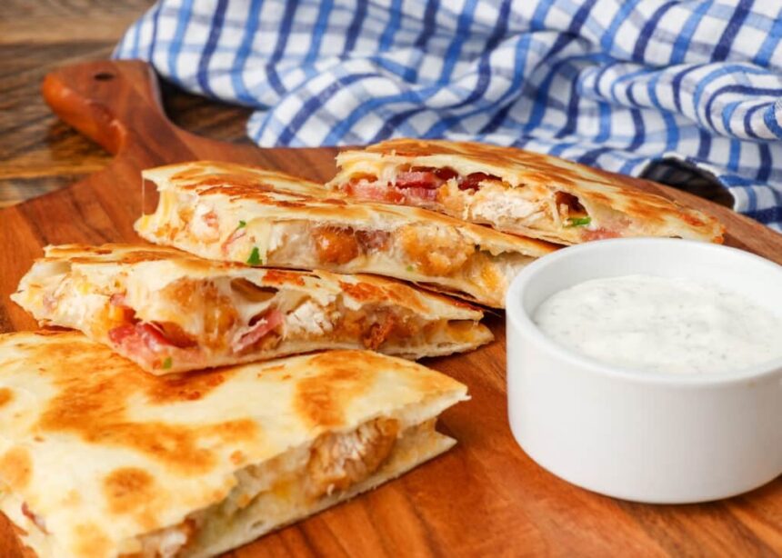 Chicken, bacon, quesadillas on cutting board with a side of ranch dip