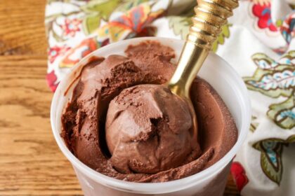 A horizontal photo of a freezer safe container on a wooden tabletop with a floral tea towel visible in the background.