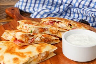Chicken, bacon, quesadillas on cutting board with a side of ranch dip
