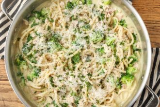 A close up horizontally aligned photo of a skillet full of chicken broccoli pasta.
