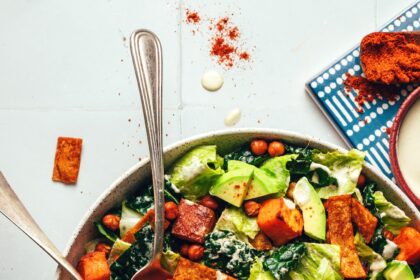 Serving spoon and fork resting in a bowl of our vegan sweet potato chickpea taco salad